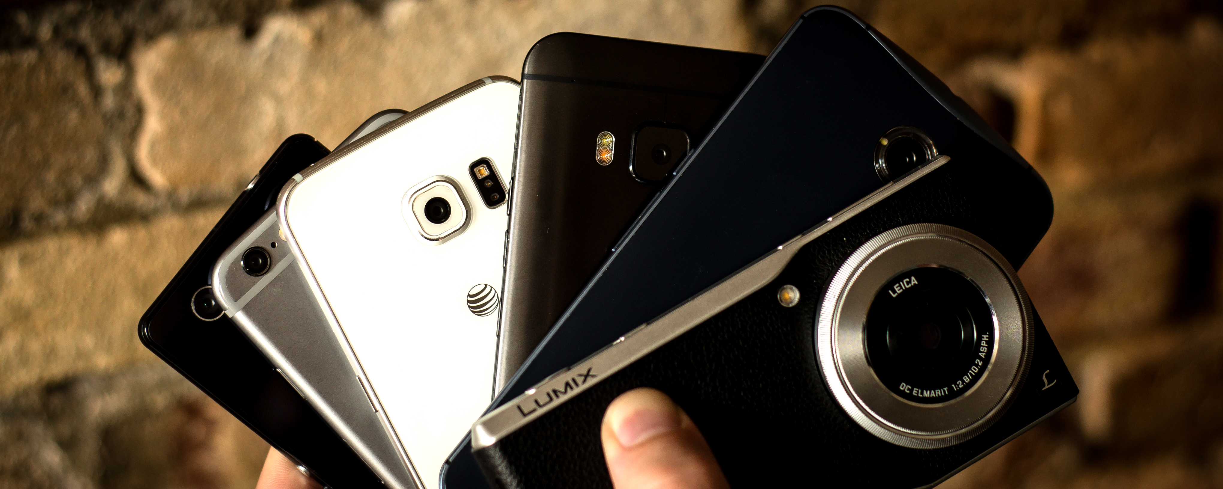  A hand holding a Panasonic Lumix smartphone, an LG G4 smartphone, and an Apple iPhone 6s smartphone.