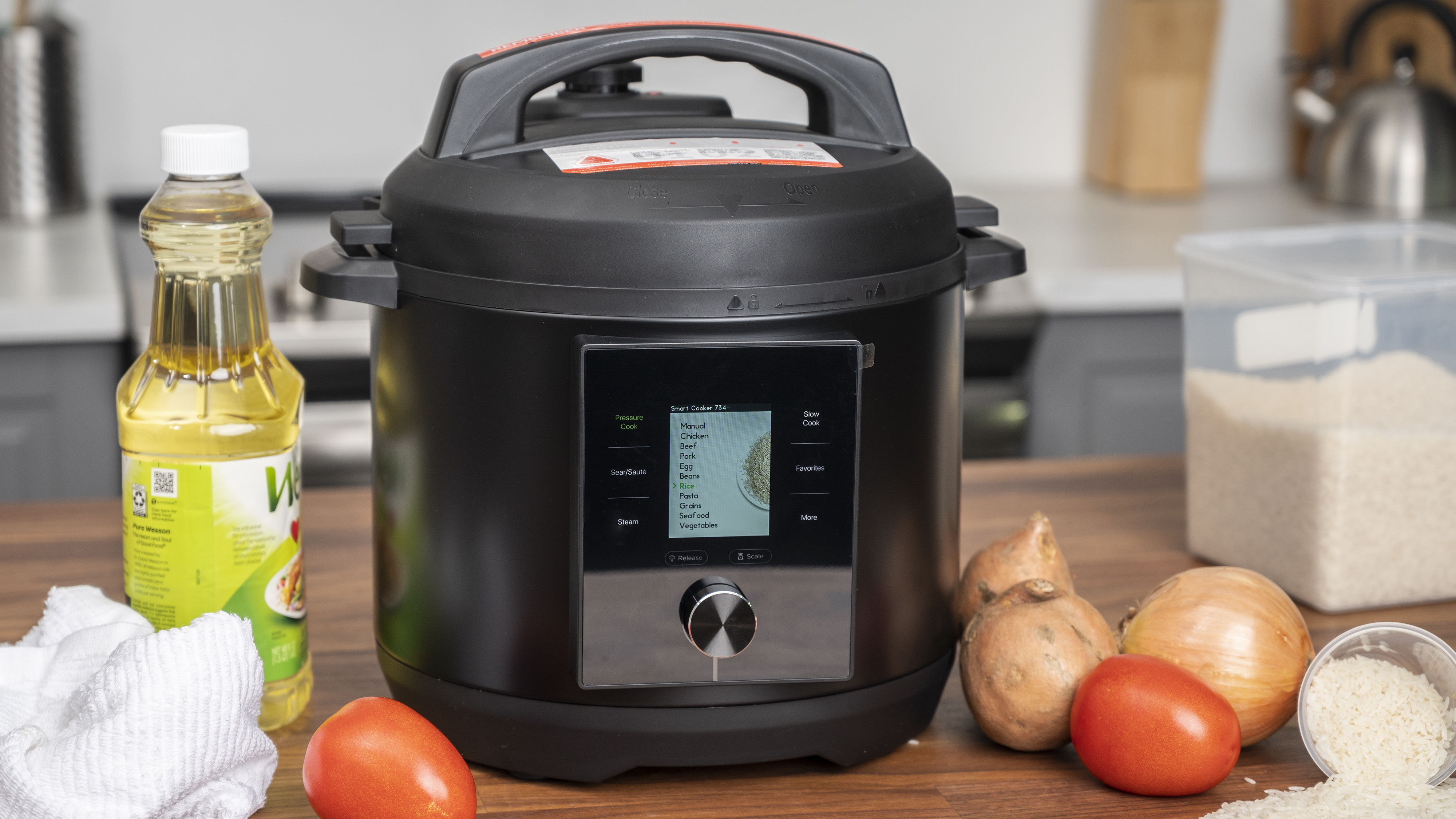 Скороварка Chef iQ стоит на столе, выложенном белой плиткой, а на разделочной доске лежат свежие продукты.