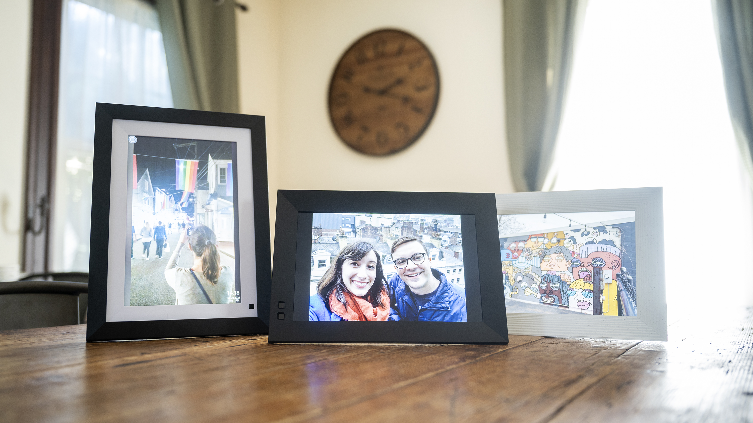 Três quadros de imagens digitais exibindo fotos de família sentam -se em uma mesa de madeira