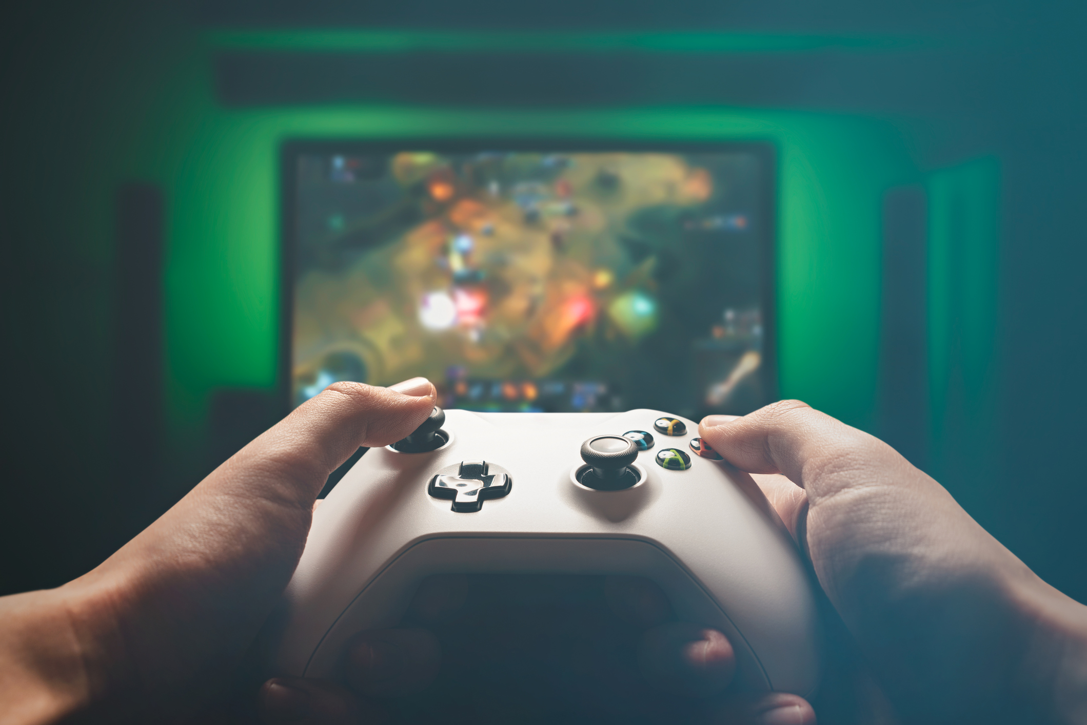 A man's hands hold a gaming controller while playing a RPG on a TV.