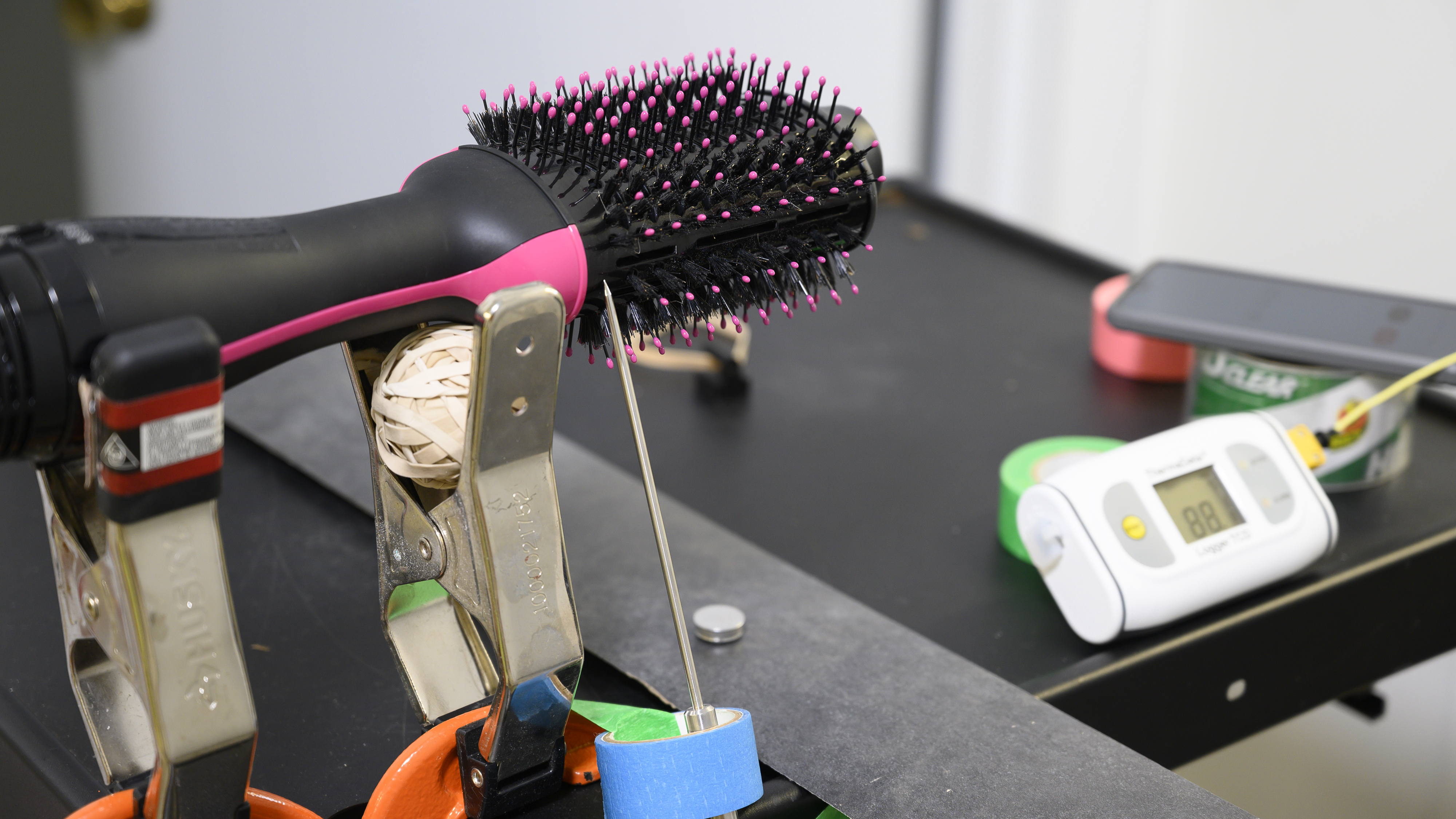 A hair dryer brush sitting with a temperature probe resting against it.