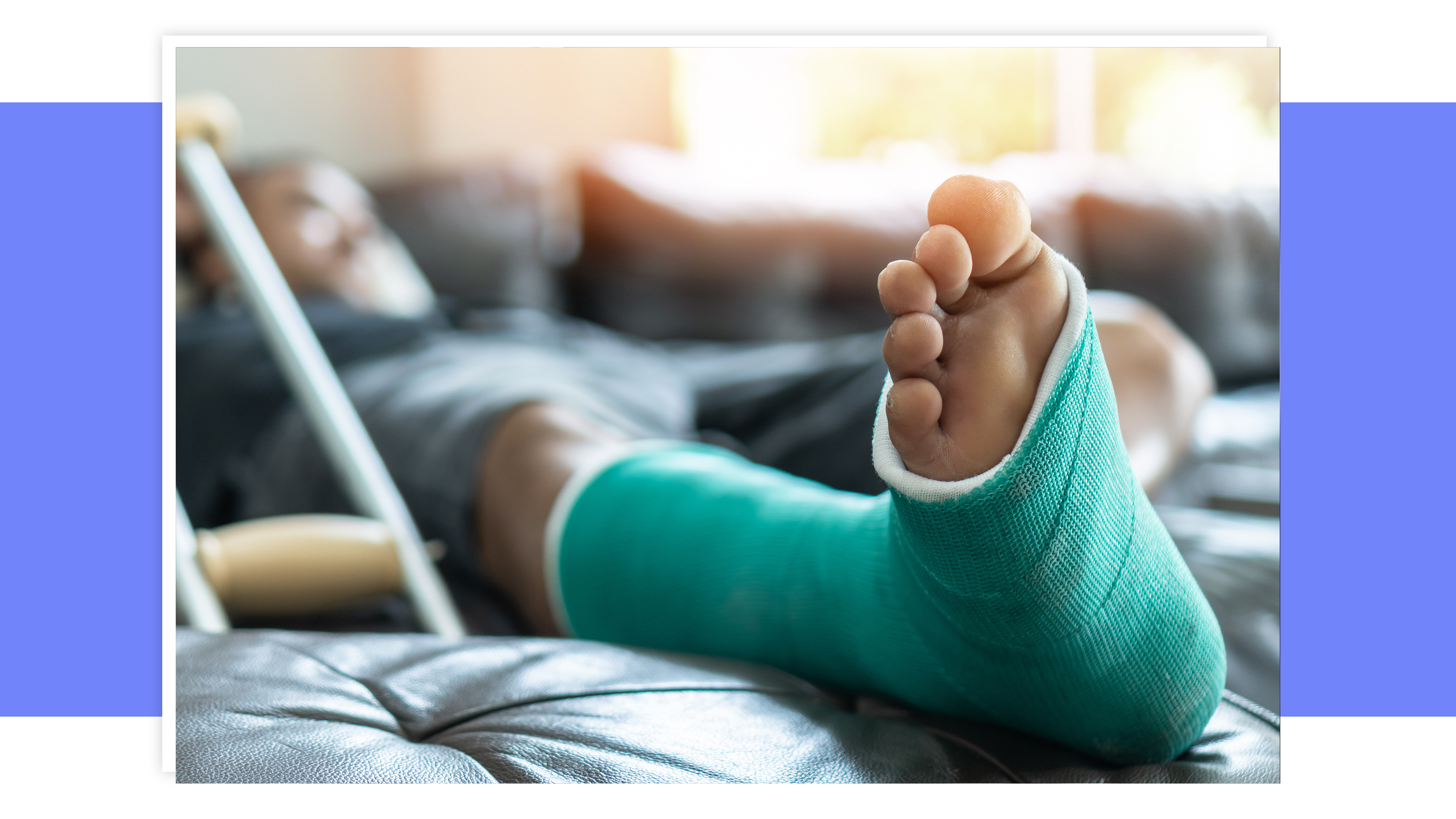 Person sitting on couch with injured foot elevated on pillow to rest it while disabled.