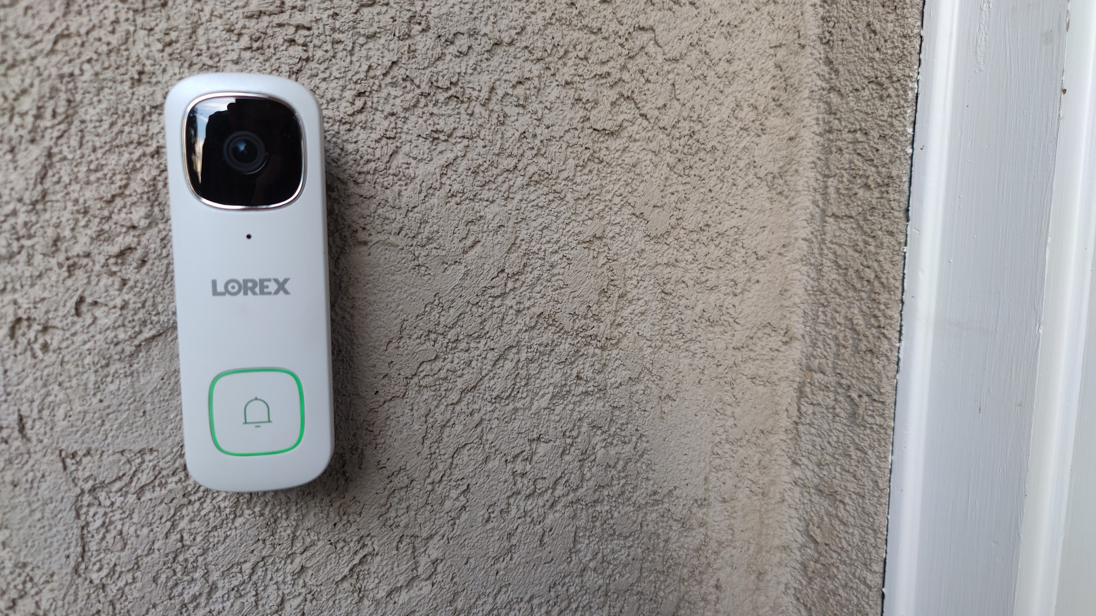 White Lorex 2K Wired Video Doorbell montado na parede em casa ao ar livre