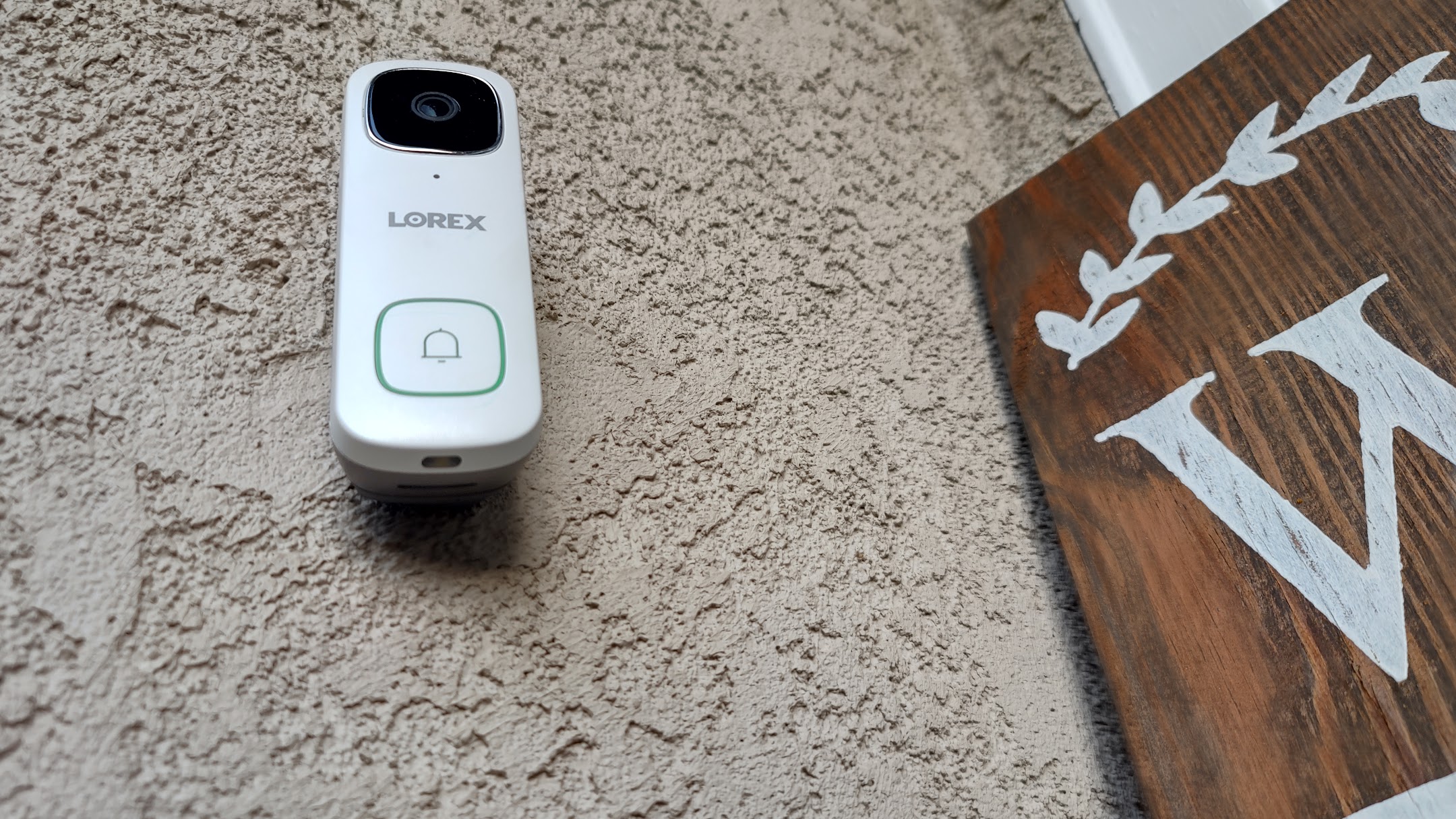 White Lorex 2K Wired Video Doorbell montado na parede em casa ao ar livre