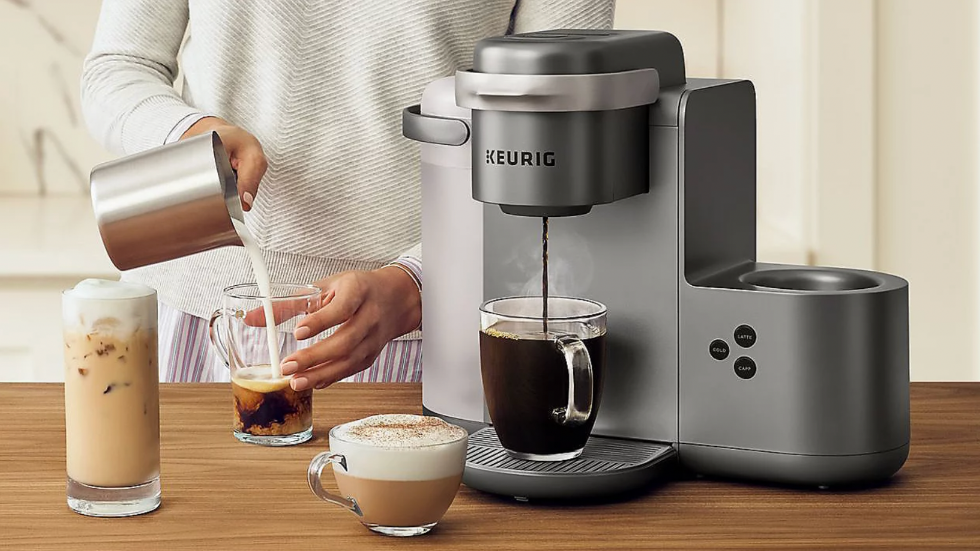 A person pours a cup of coffee from a Keurig machine.