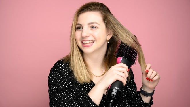 A woman drying her hair with a hairdryer.