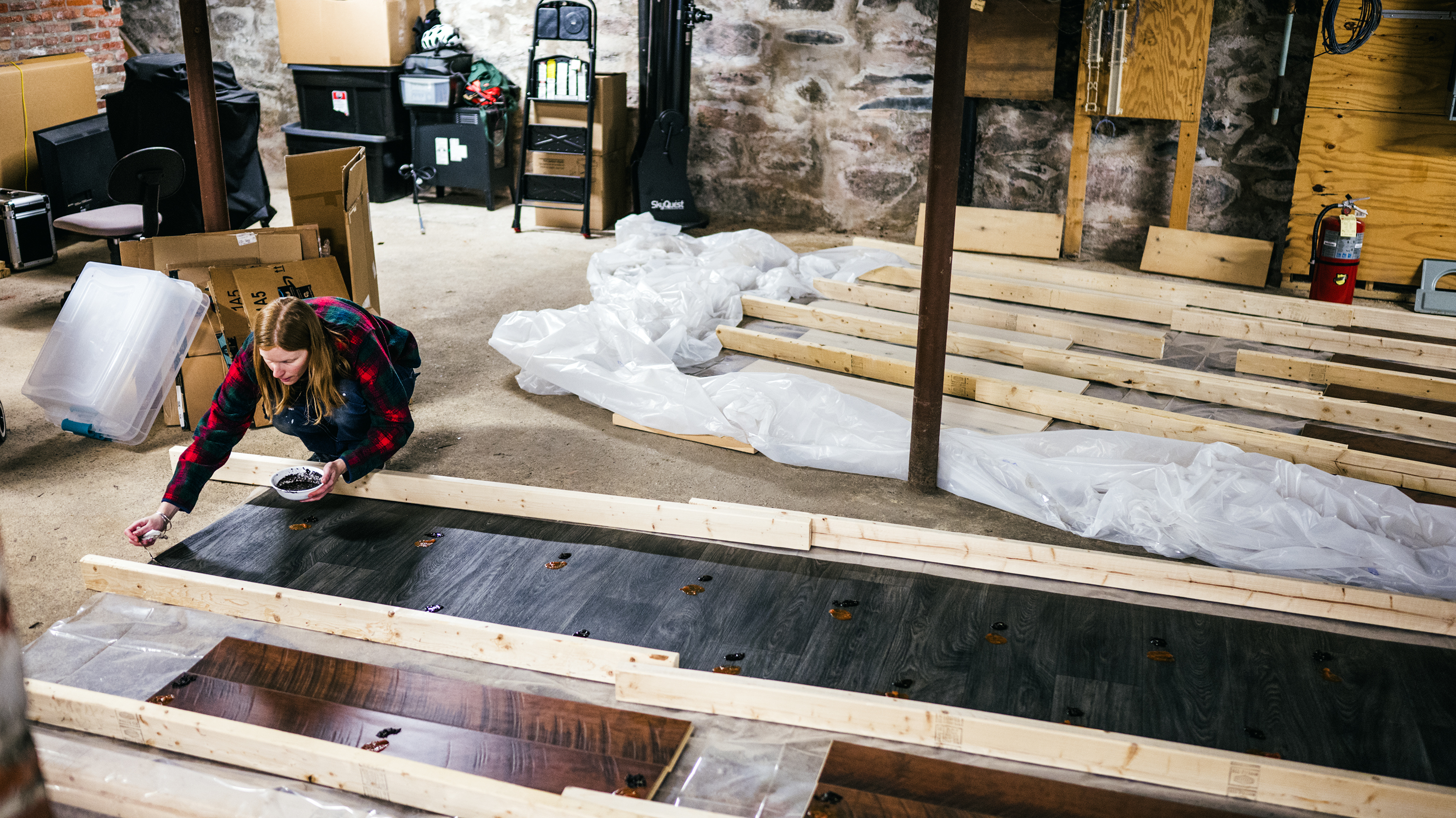 A woman applies stains to hardwood floor surfaces for testing purposes.