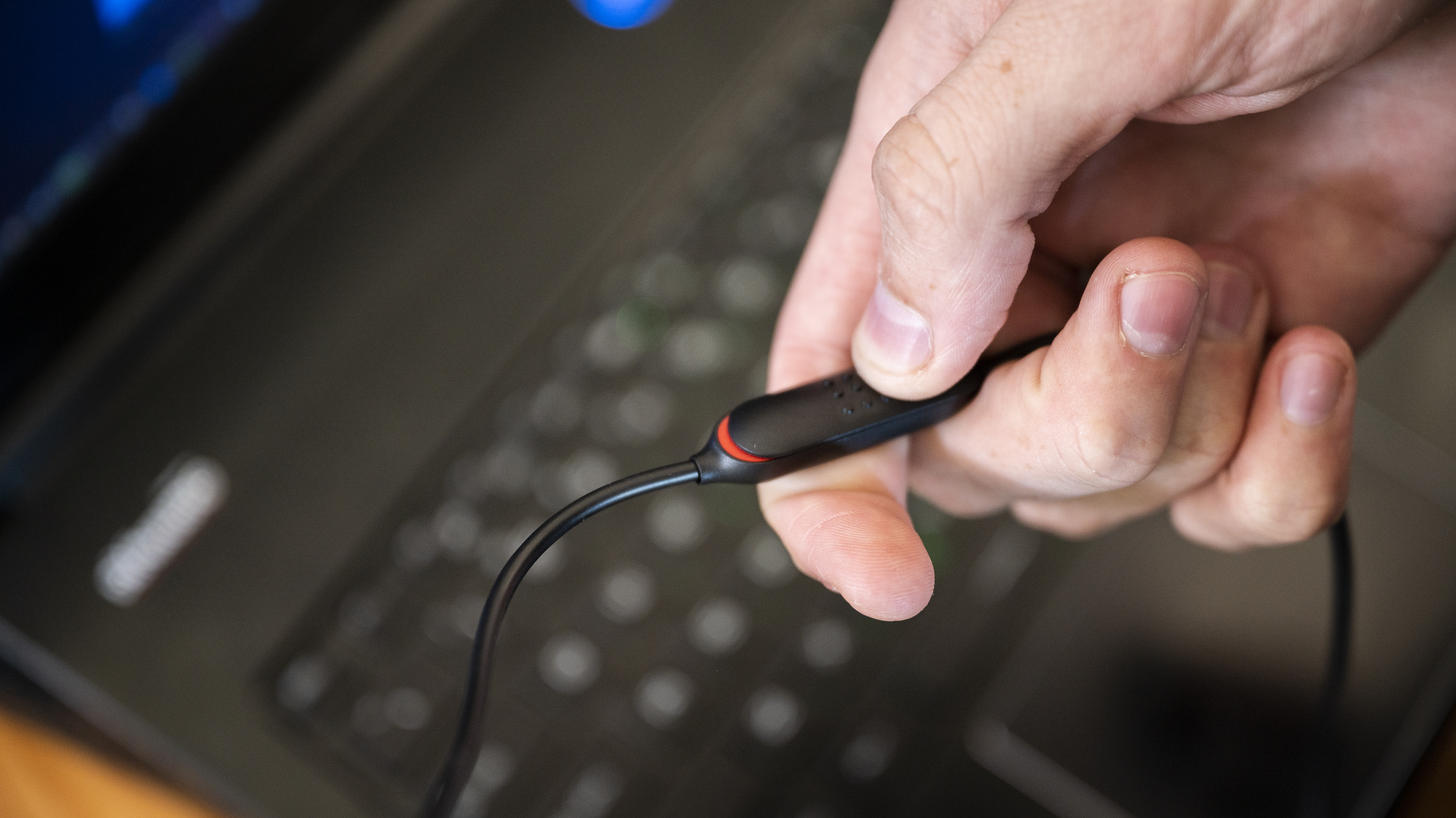 Fingers gripping a small plastic rectangle attached to a wire.