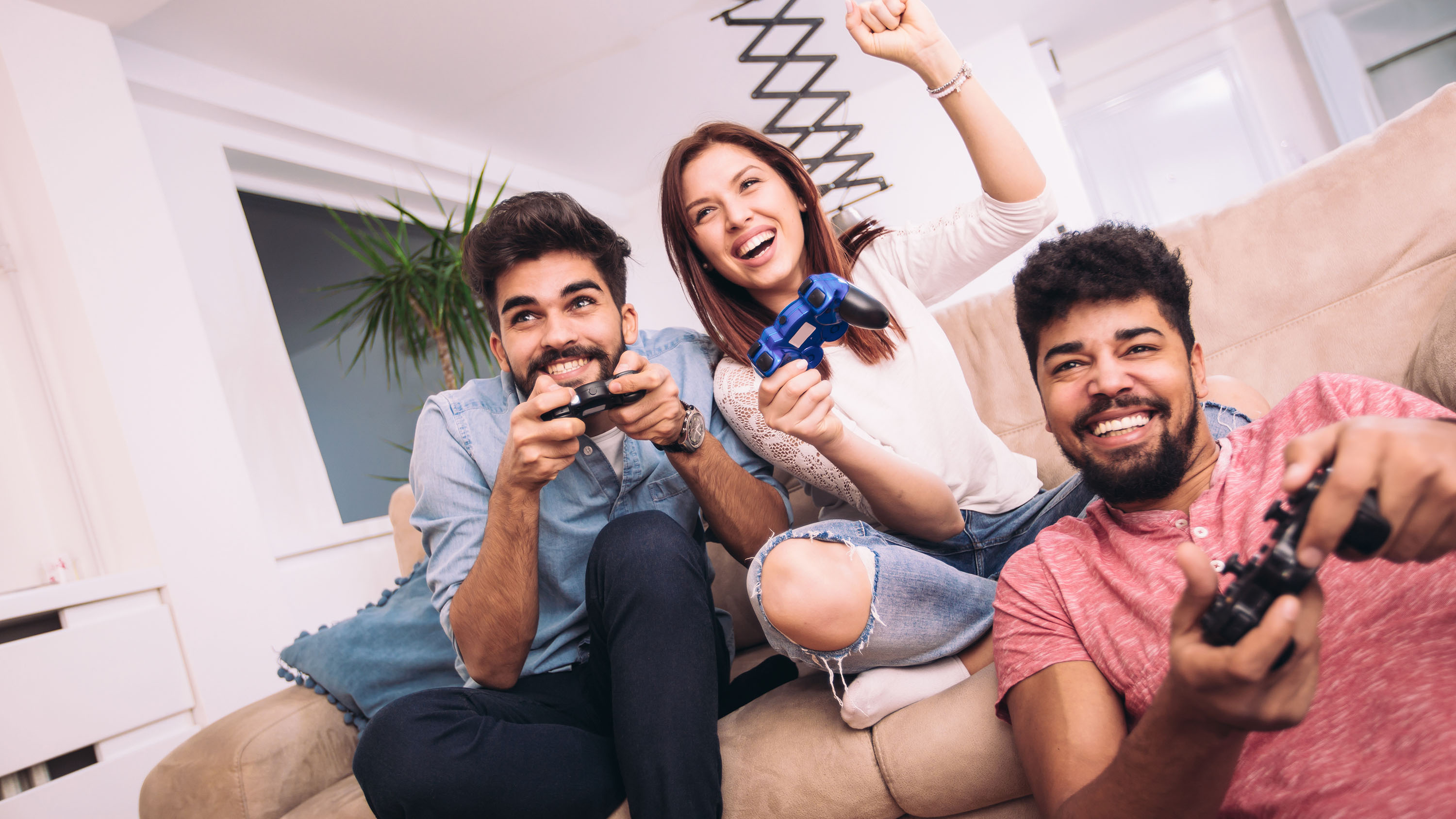 Group of friends play video games together having fun at home