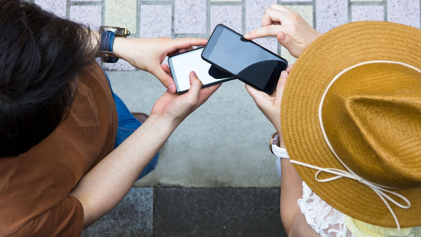 Two people holding phones over each other