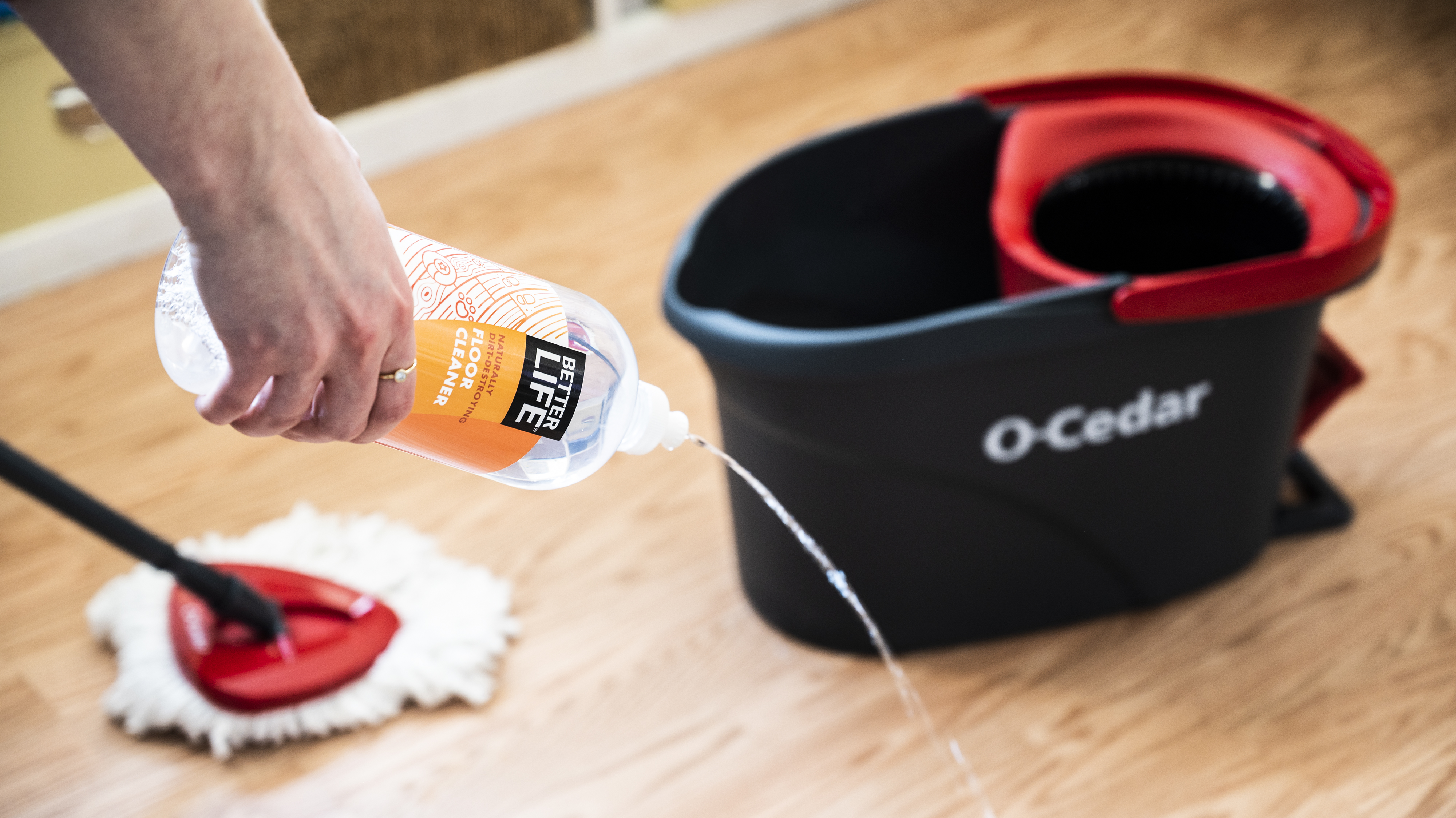 a person squirts Better Life Naturally Dirt-Destroying Floor Cleaner on a floor