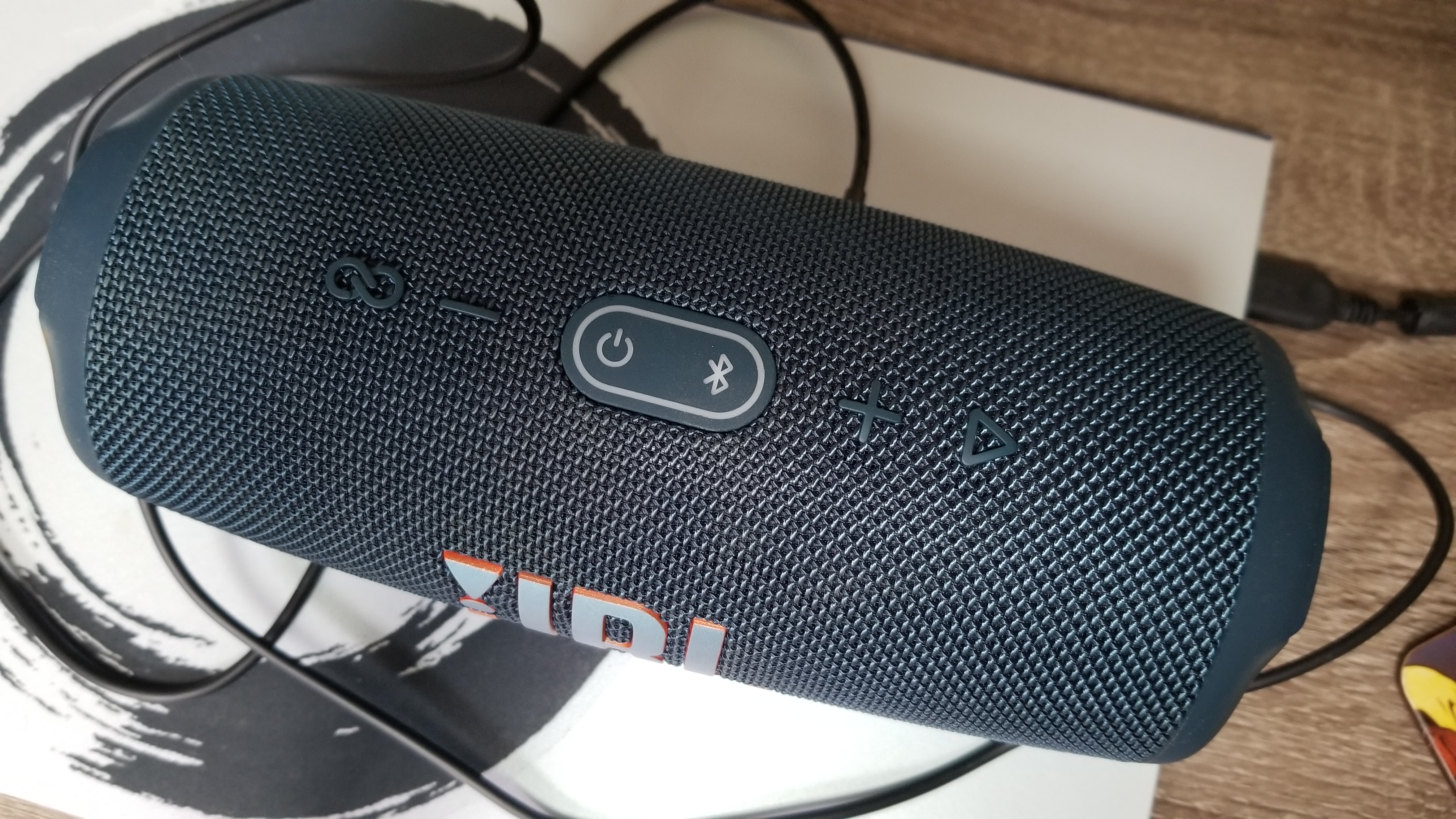 Top down view of the JBL Charge 5, plugged into a silver laptop via USB-C