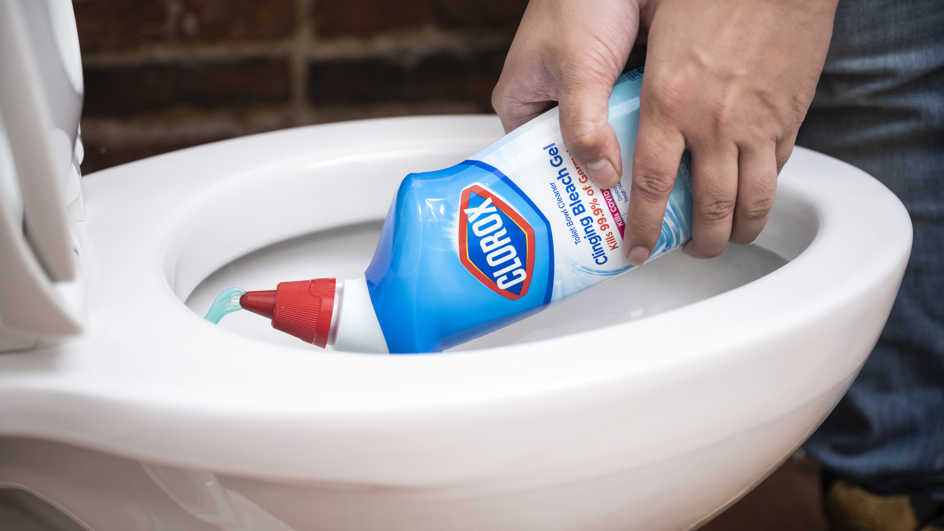 A person squirts liquid cleaner into the bowl of a toilet